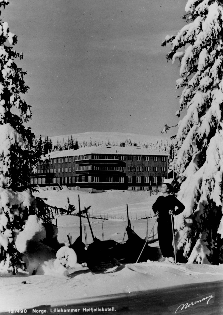 Avfotografert postkort. En kvinnelig skiløper foran Lillehammer høyfjellshotell.