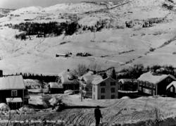 Avfotografert postkort. En mannlig skiløper foran Bauker går