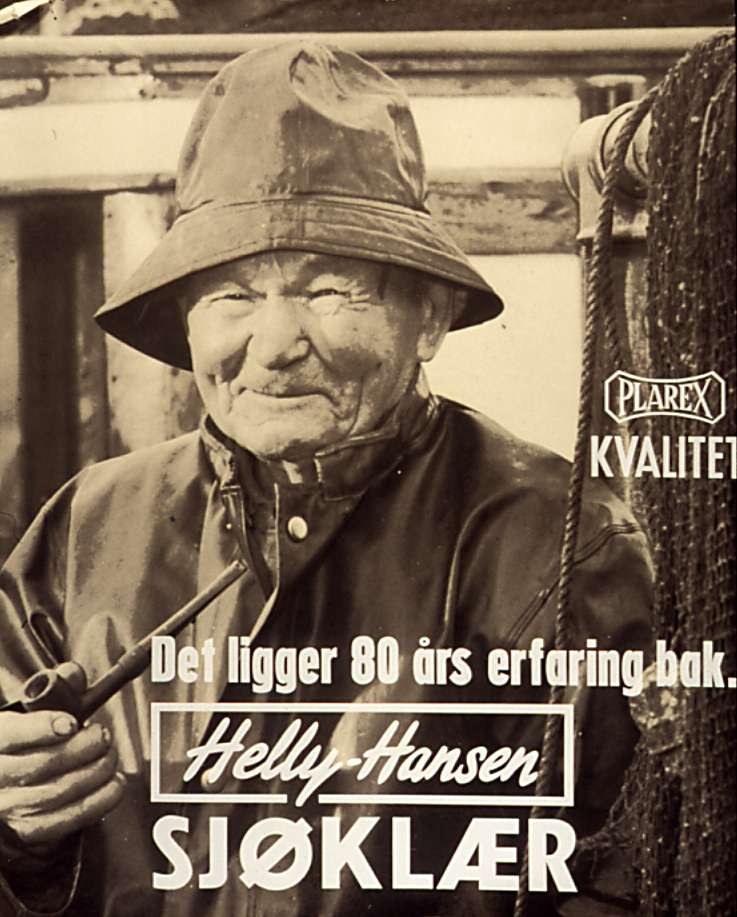 Reklame for Helly Hansen regntøy. Yrkesfisker Karl Ludvig Hansen er modell med sydvest og pipe i hånden.
