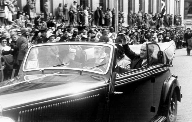 Fra Oslo under fredssdagene i 1945.Rektor Seip med frue i åpen bil med sjåfør.
Publikum i bakgrunnen.