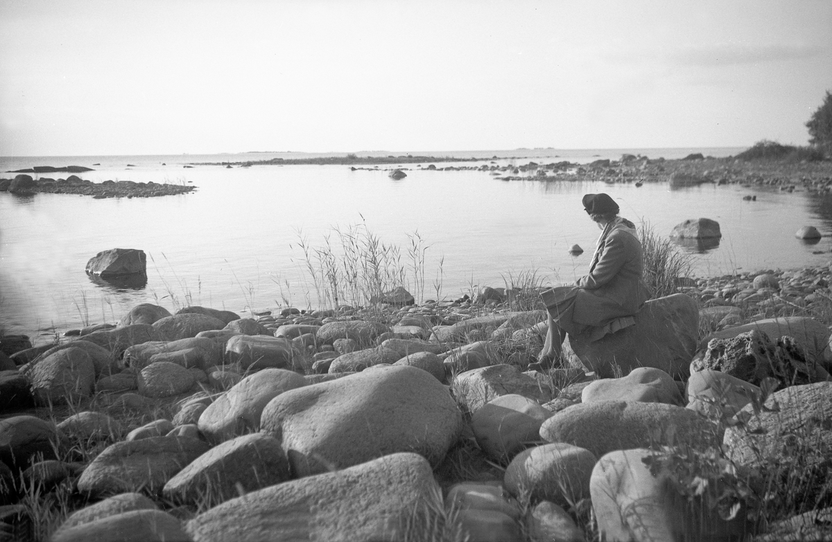 Dordi Arentz sitter på en stein i vannkanten ved Vänern i Sverige. Fotografert under en biltur i Danmark og Sverige 1947.