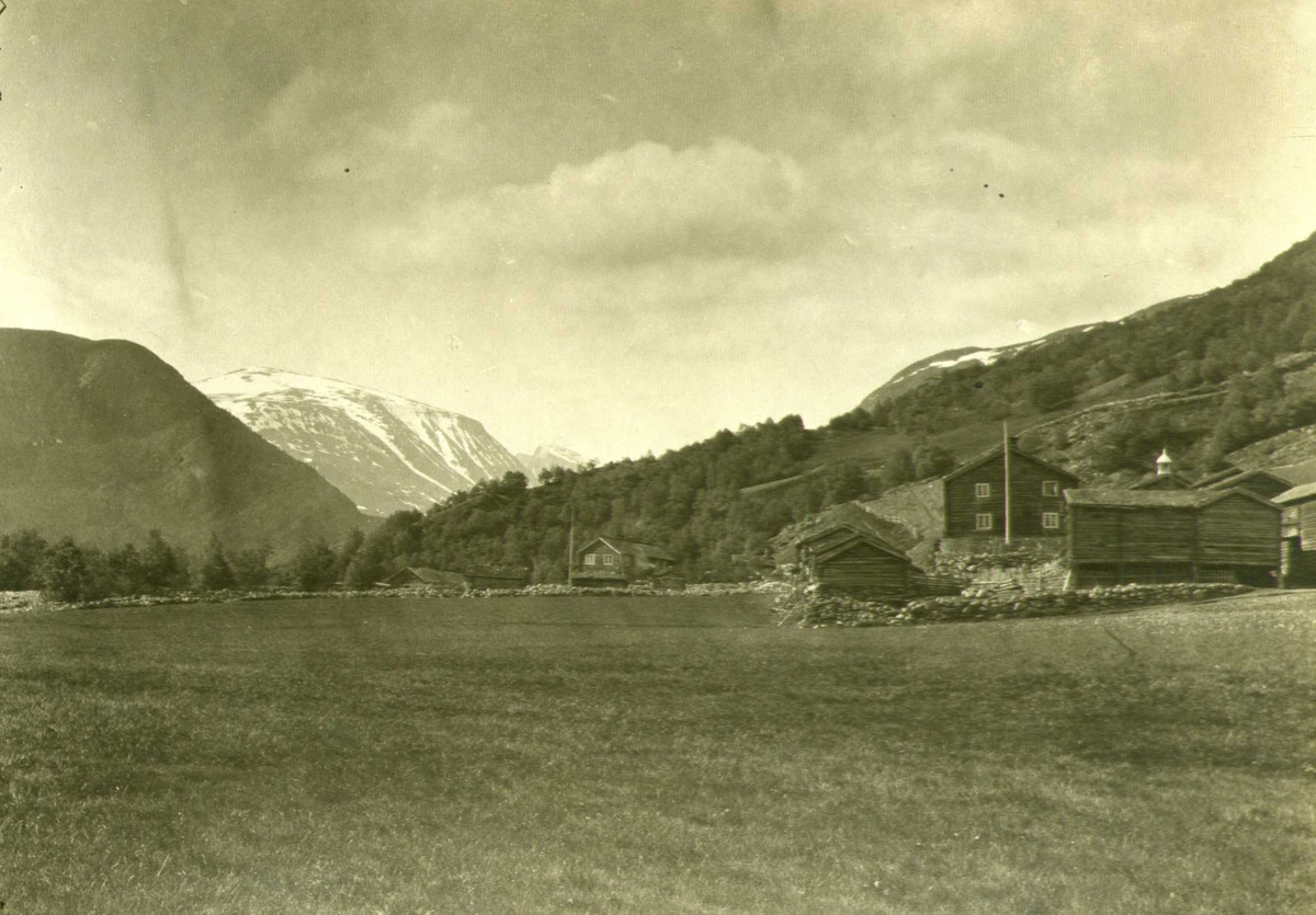 Gårdstun, Sulheim, Lom, Oppland. Landskap med utsikt mot Galdhøpiggen. Fotografert 1915.