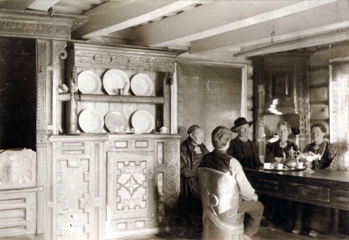 Stueinteriør innredet av Tarald Olsen i 1811, Skoje, Sauland, Hjartdal, Telemark. Familie sittende rundt bordet. Fotografert 1907.