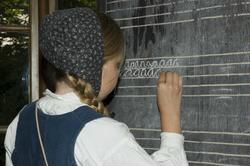 Levendegjøring på museum.Ferieskolen uke 31. Elev skriver p