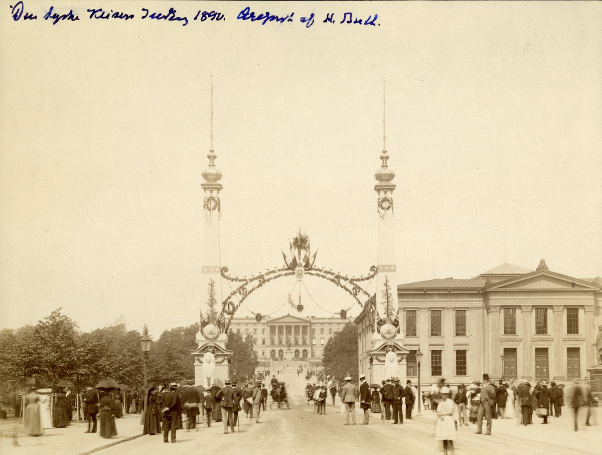 Fra keiser Wilhelms besøk i Kristiania i 1890. Æresportal av H. Bull på Karl Johans gate med Universitetet og Slottet i bakgrunnen. Tilskuere langs veien