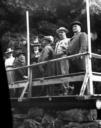 Gruppe mennesker stående på plattform/brygge i tre. Fjell/be