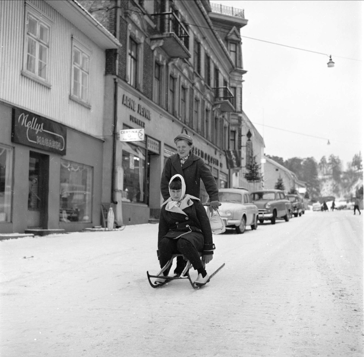 Gjøvik, gatebilde, mann med sparkstøtting og dame som passasjer, 03.01.1961
