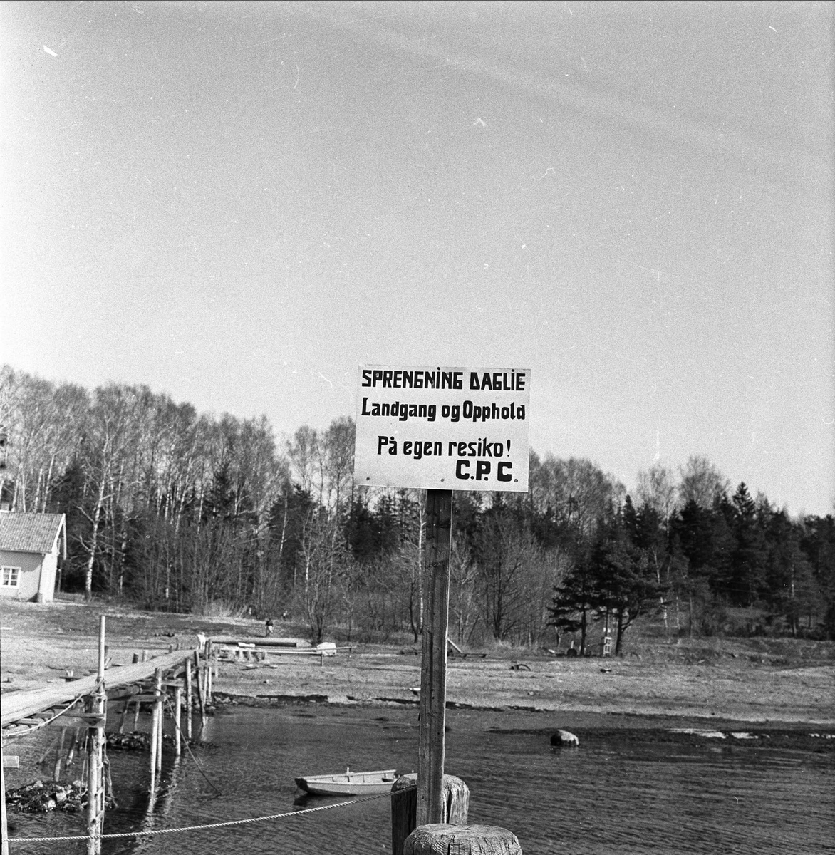 Usikkert om dette er fra Tokke i Telemark. Skilt med advarsel om sprengning.
Pir ut i vannet med robåt. Fotografert i 1957.