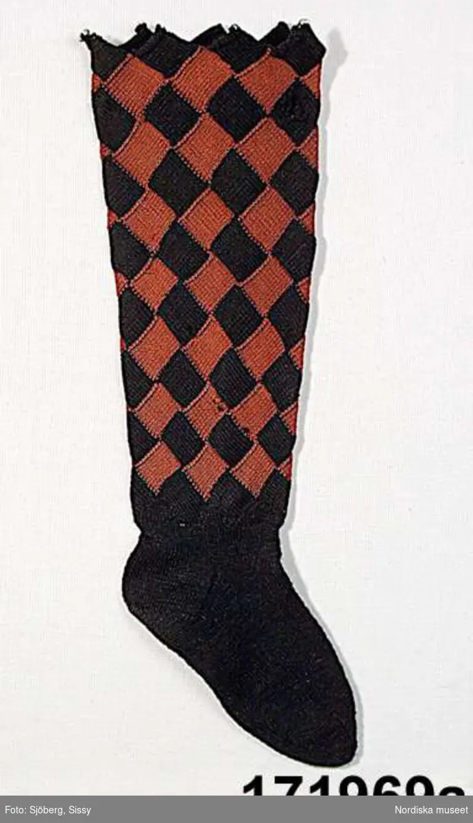 A-B. Strumpa för kvinna, ett par.
S-tvinnat ullgarn.
Stickad i slätstickning, foten enfärgad svart, skaftet stickat i näverstickning rutigt i rött/svart.
/Berit Eldvik 2002
