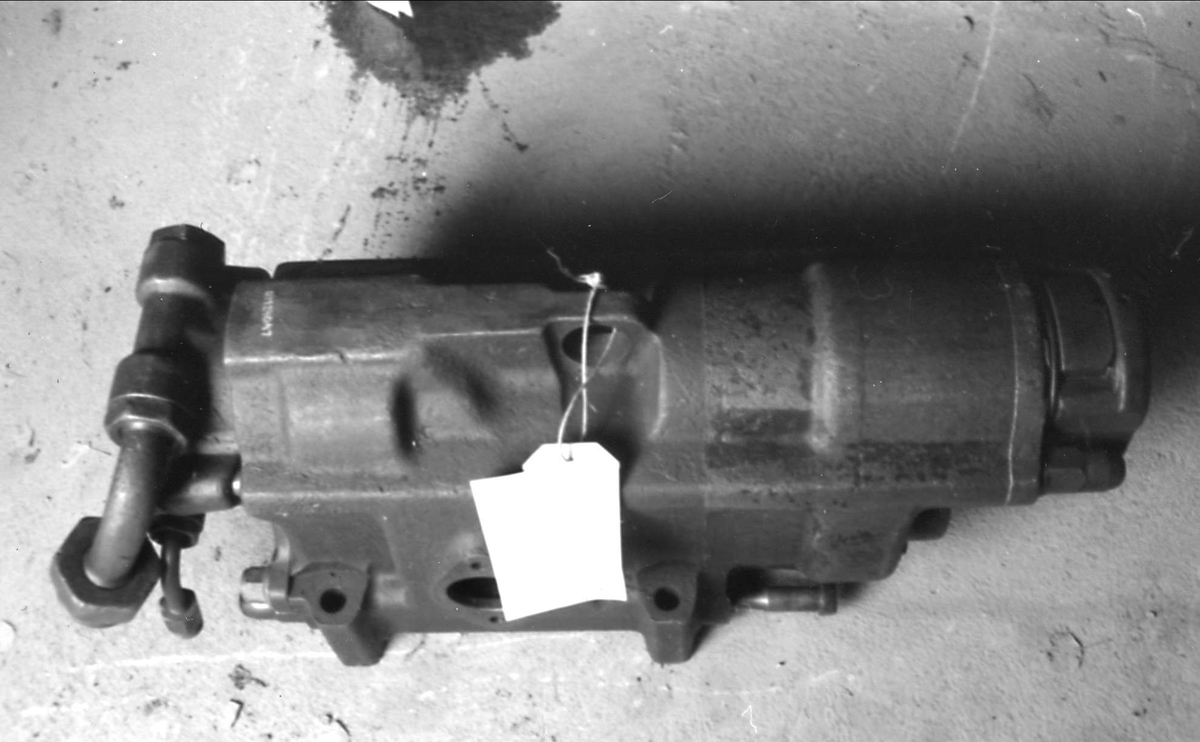 Tryckluftsdriven borrmaskin för ortdrivning, tillverkad av stålgjutgods, med ett flertal kopplingar, troligen för tryckluft och vatten.
