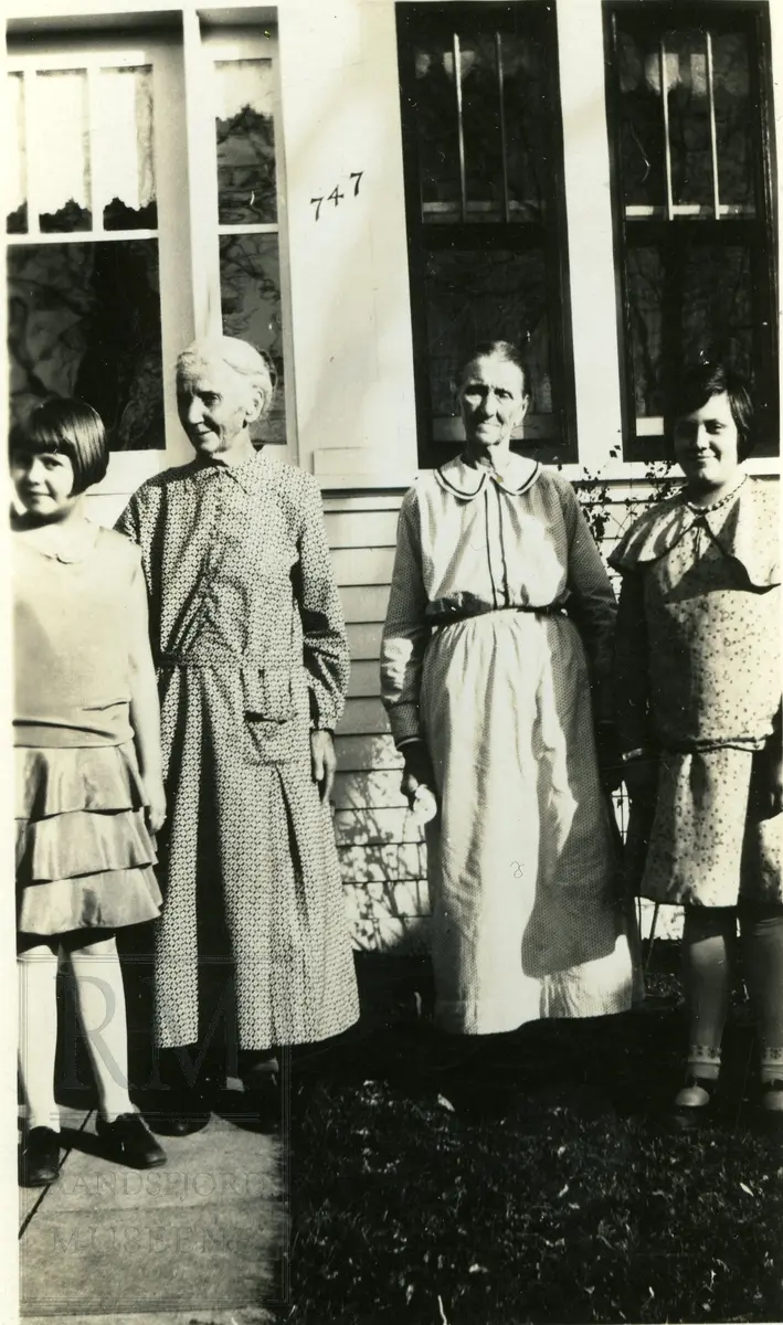 Tre kvinner og en jente stående utenfor et hus.