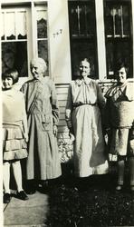 Tre kvinner og en jente stående utenfor et hus.