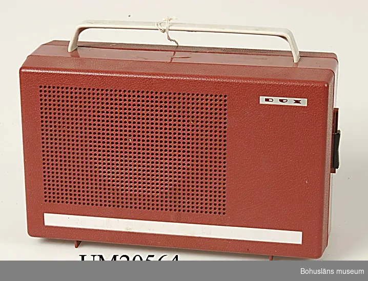 Batteridriven grammofon med högtalare ihopsättbara till bärbar enhet.
Röd och grå plast. De röda plastdelarna har ett lågmält präglat mönster i relief.
Handtaget är grått.

Ett föremål som på 1960-talet hade stor attraktionskraft bland tonåringar.