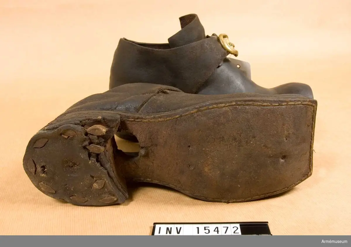 Ett par skor av brunt läder med mässingsspännen.