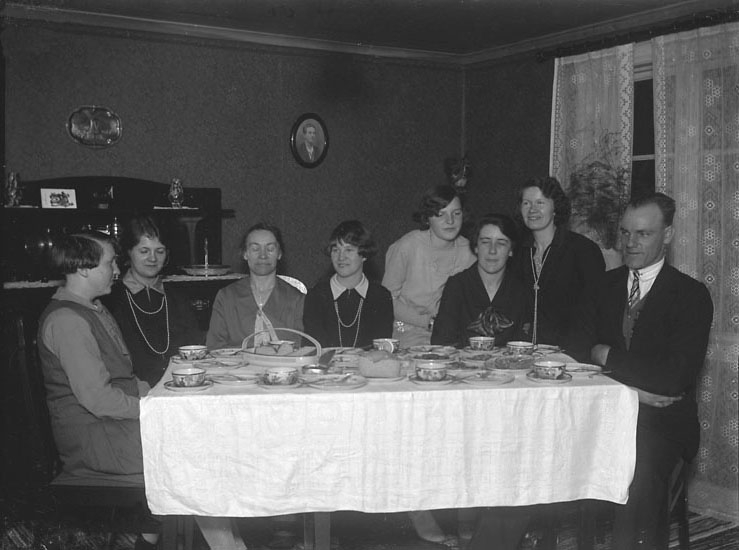Enligt senare noteringar: "Sju kvinnor och en herre vid ett kaffebord. Det finaste porslinet ("te-tyt") är framdukat till Karl Persson, Axia, Tekla Börjesson, Judith Johansson, Märta Hansson, Eina Johansson, Signe Boman och Natalia Olsson".