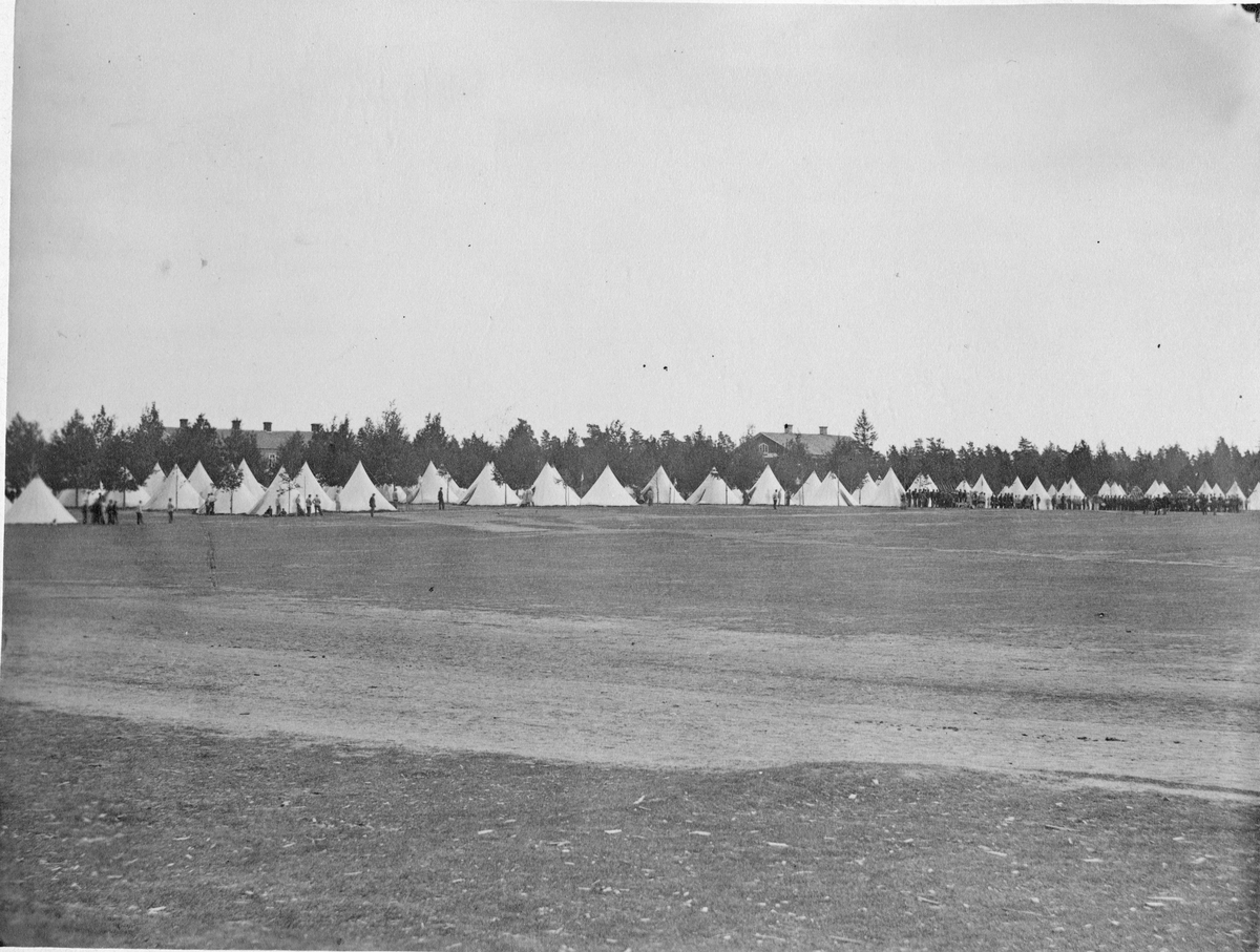 Lägerplats på Skillingaryd hed. I bakgrunden gupper av soldater framgör en mängd tält. Stora träd skymmer byggnader i bakgrunden.