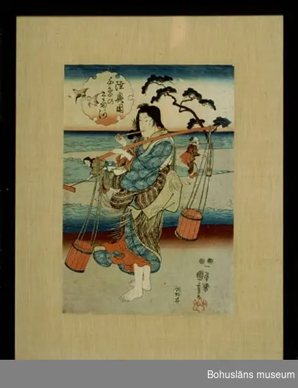 Tre kvinnor på en sandstrand som med stor sannolikhet samlar in salt. Två av kvinnorna har ämbar, en kvinna har ett redskap att raka samman med.
Kvinnan närmst i bild har någon form av rökverk i munnen.
Ett barrträd och en "pratbubbla" med japanska skrifttecken och två flygande fåglar. I bubblan står det troligen "Från Aomori", en ort på norra Honshu dvs på den japanska huvudön.