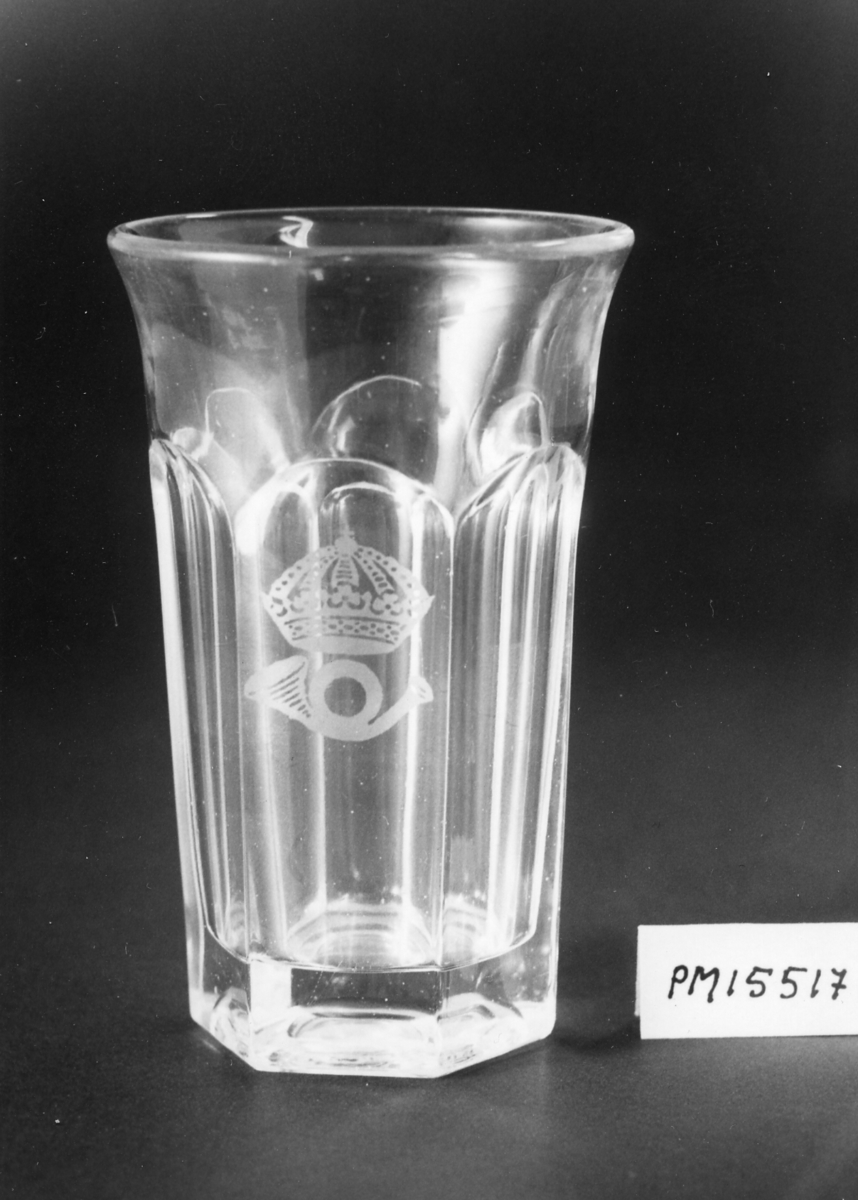 Dricksglas av ofärgat glas, sexkantigt, men runt upptill. På sidan ett krönt posthorn av 1912 års modell.