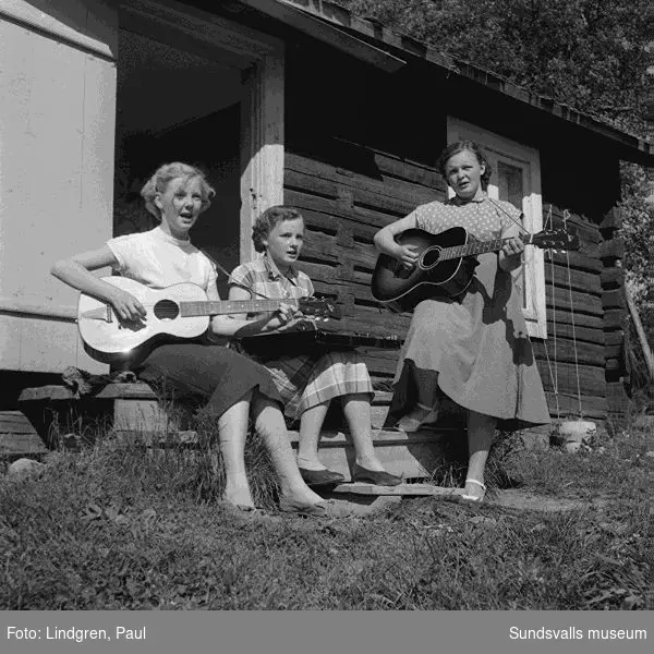 Fäbod i Norrböle, Attmar. Tre kvinnor spelar gitarr och zittra, kvinna med kossor.