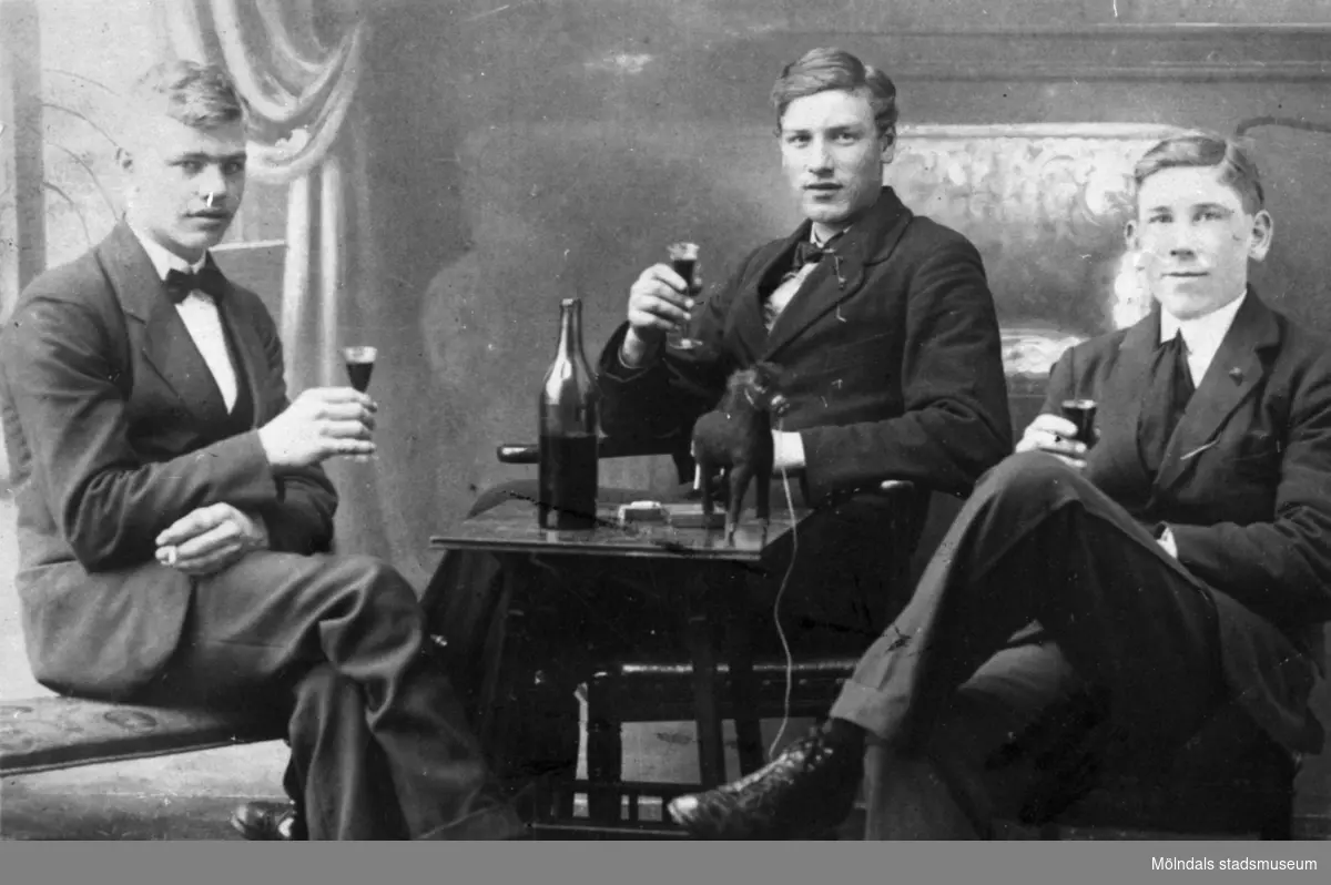 Tre män i kostym sitter runt ett bord med var sitt glas i handen. Från vänster: man med okänd identitet, Ivar Dahlberg och Willy Jansson. Mölndal, okänt årtal.