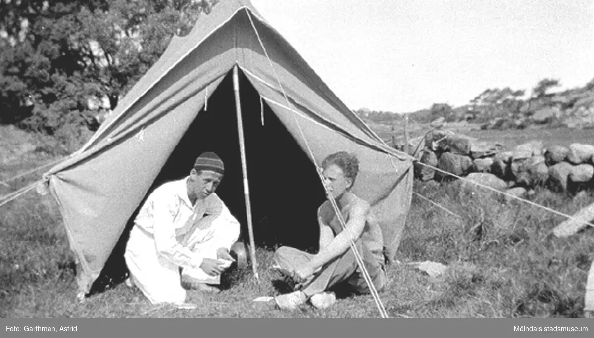 Bror Eriksson och Helmer Garthman spelar kort framför ett upprest tält i Fjärås, 1930-tal.