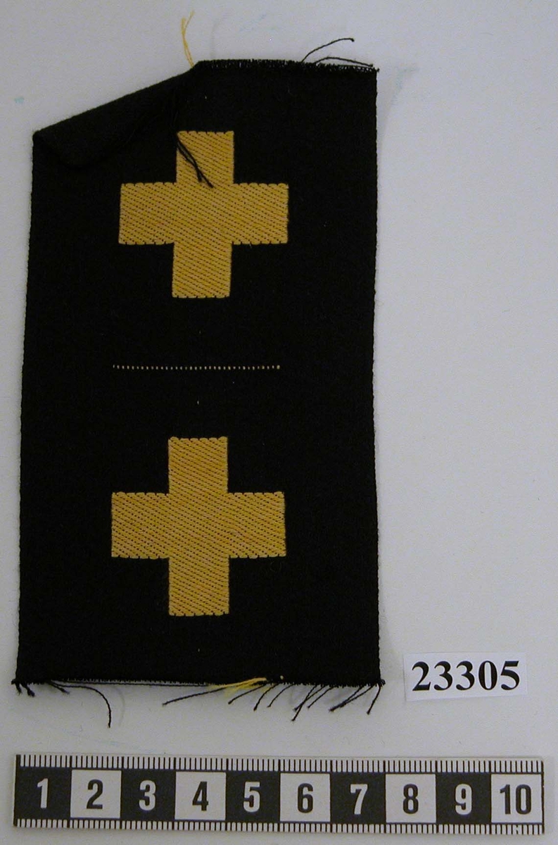 Yrkesemblem och gradbeteckning (ett par) för stamanställd menig, sjukvårdare. Ett kors vävt i gult på svart tyglapp.