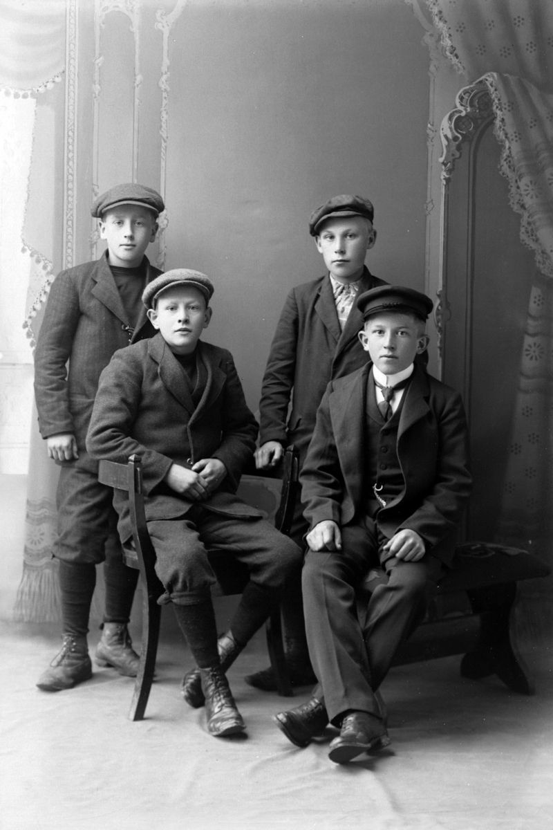 Studioportrett av fire gutter i konfirmasjonsalder.