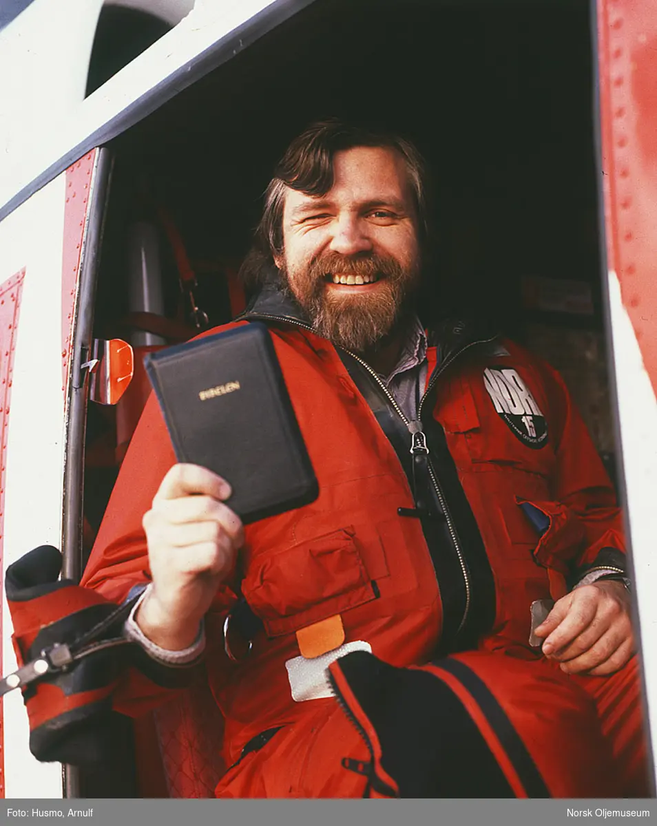 Nordsjøprest Petter Skantes holder frem bibelen i et helikopter.