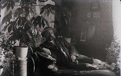 Portrett av mann som ligger på en divan i en pent innredet s