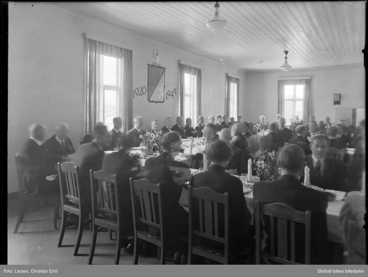 Ukjent gruppe menn rundt dekket festbord, våpenskjold på vegg 1920-1945. Borregaard i Sarpsborg.
