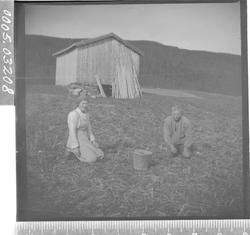 Portrett av mann og kvinne sittende på et jorde.