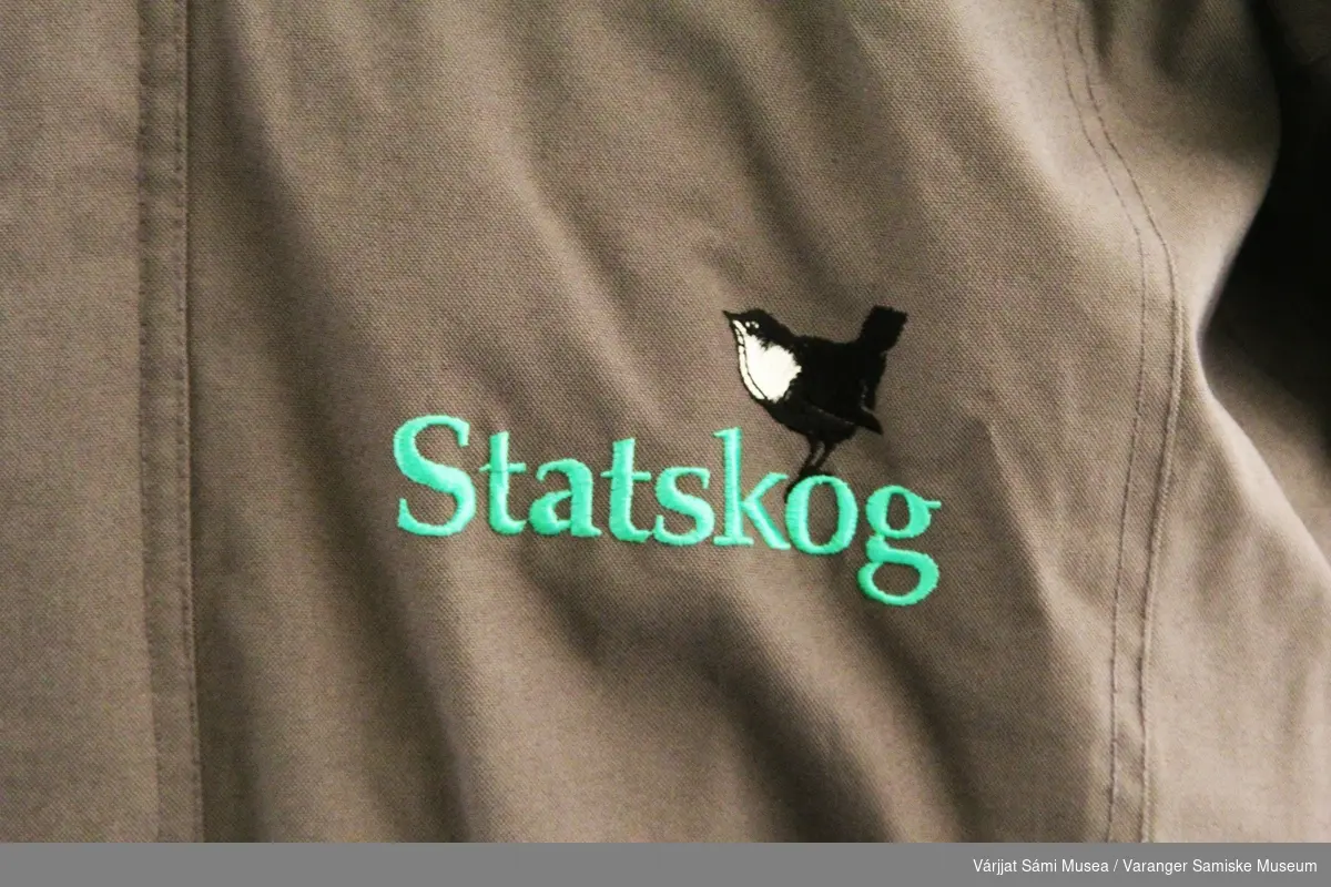 Yttterjakke merket "Statskog" i fargen koksgrå med svarte detaljer. Produsenten er Skogstad Sport AS.