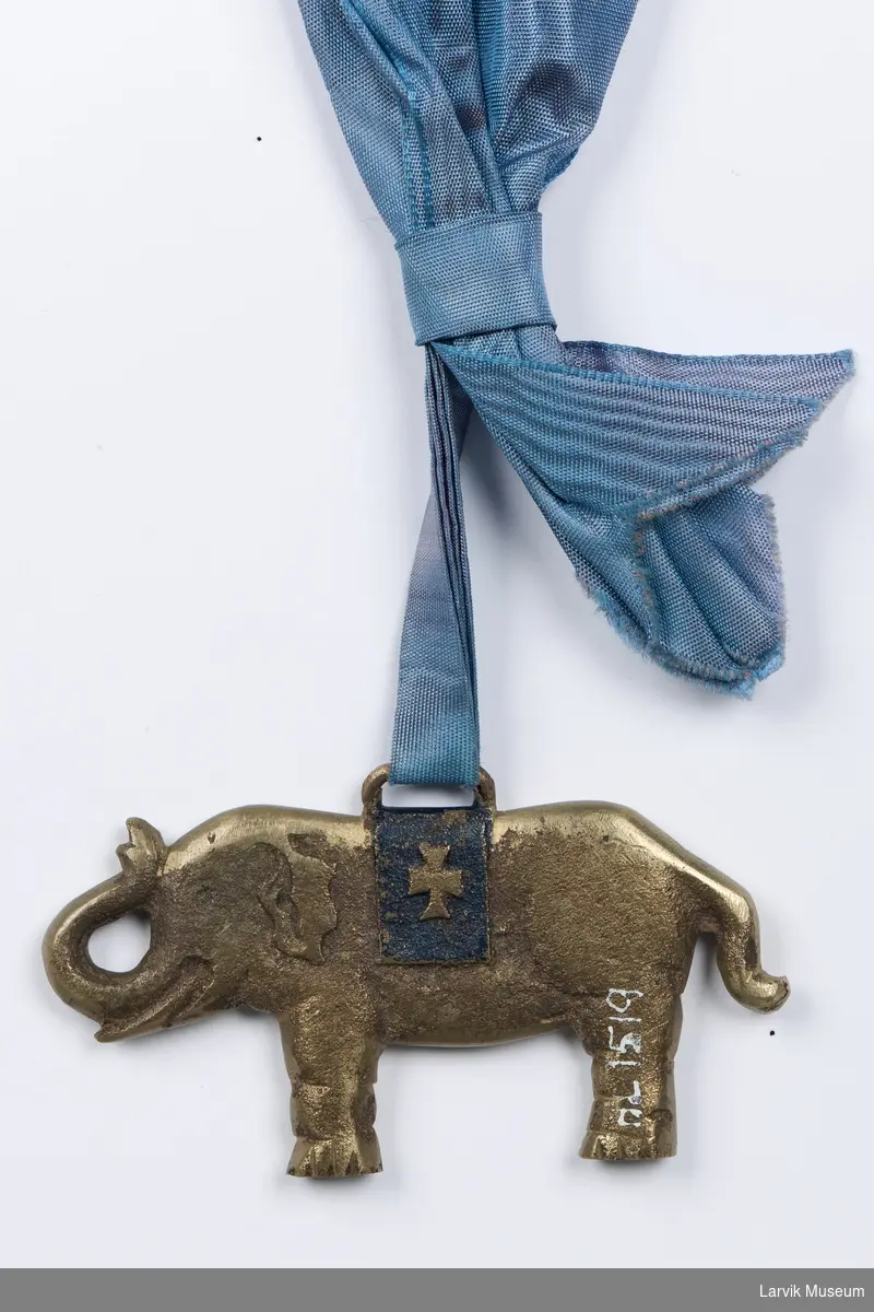 Form: messingelefant i turkisblått moiré-bånd med sløyfe
