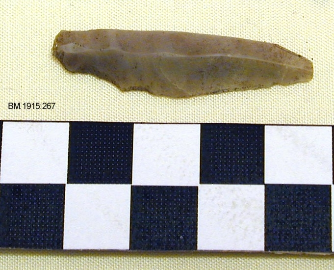 Flekkepil av lysegrå flint, som Gjessing: Rogalands steinalder, fig.186, med tangen innhugget bare fra den ene siden. 
Se TGM-BM.1915:265-67