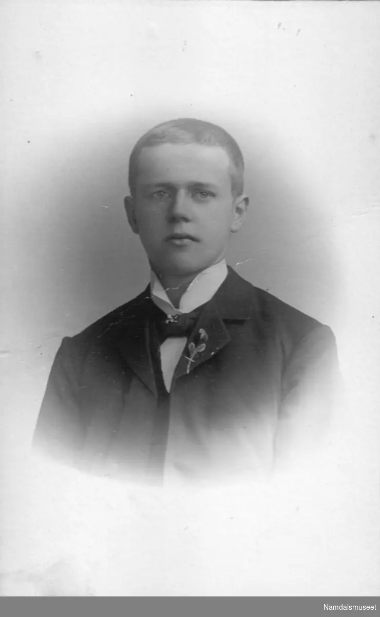 Portrett av en ung mann med blomst i jakkeslaget.