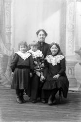 Studioportrett av kvinne og tre barn.