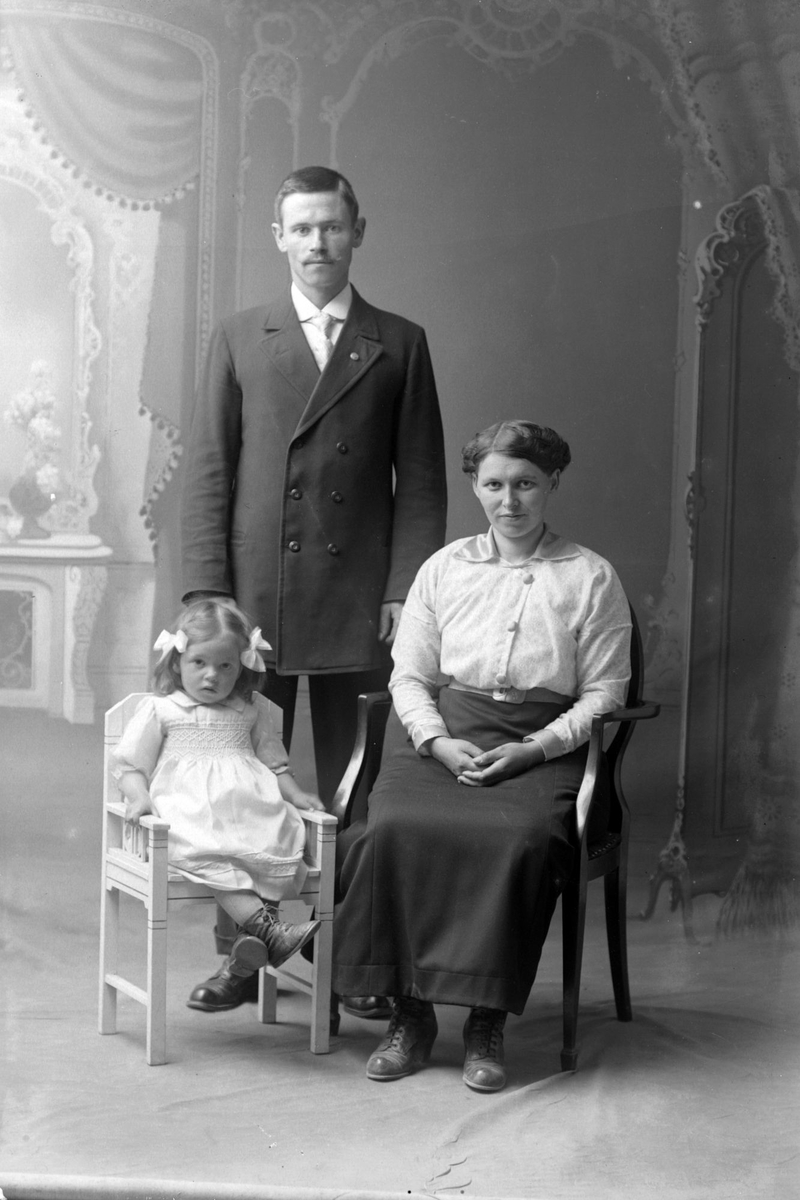 Studioportrett i helfigur av en mann, kvinne og et barn.