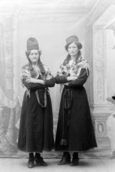 Studioportrett i helfigur av to kvinner i samiske drakter.