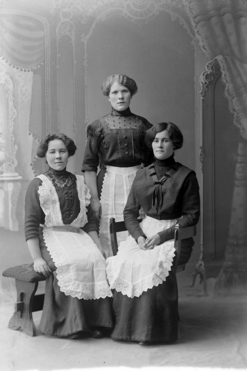 Studioportrett av tre kvinner, kledt som servitriser(?).