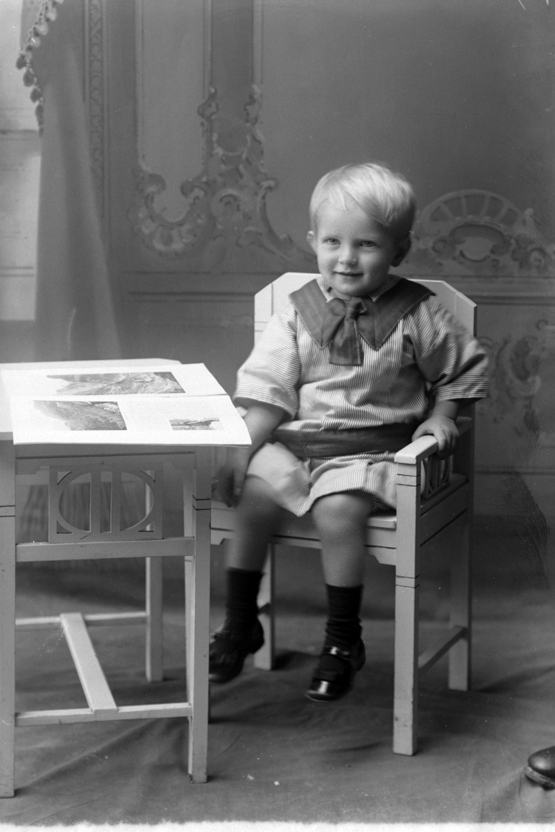 Studioportrett av en liten gutt med en billedbok.