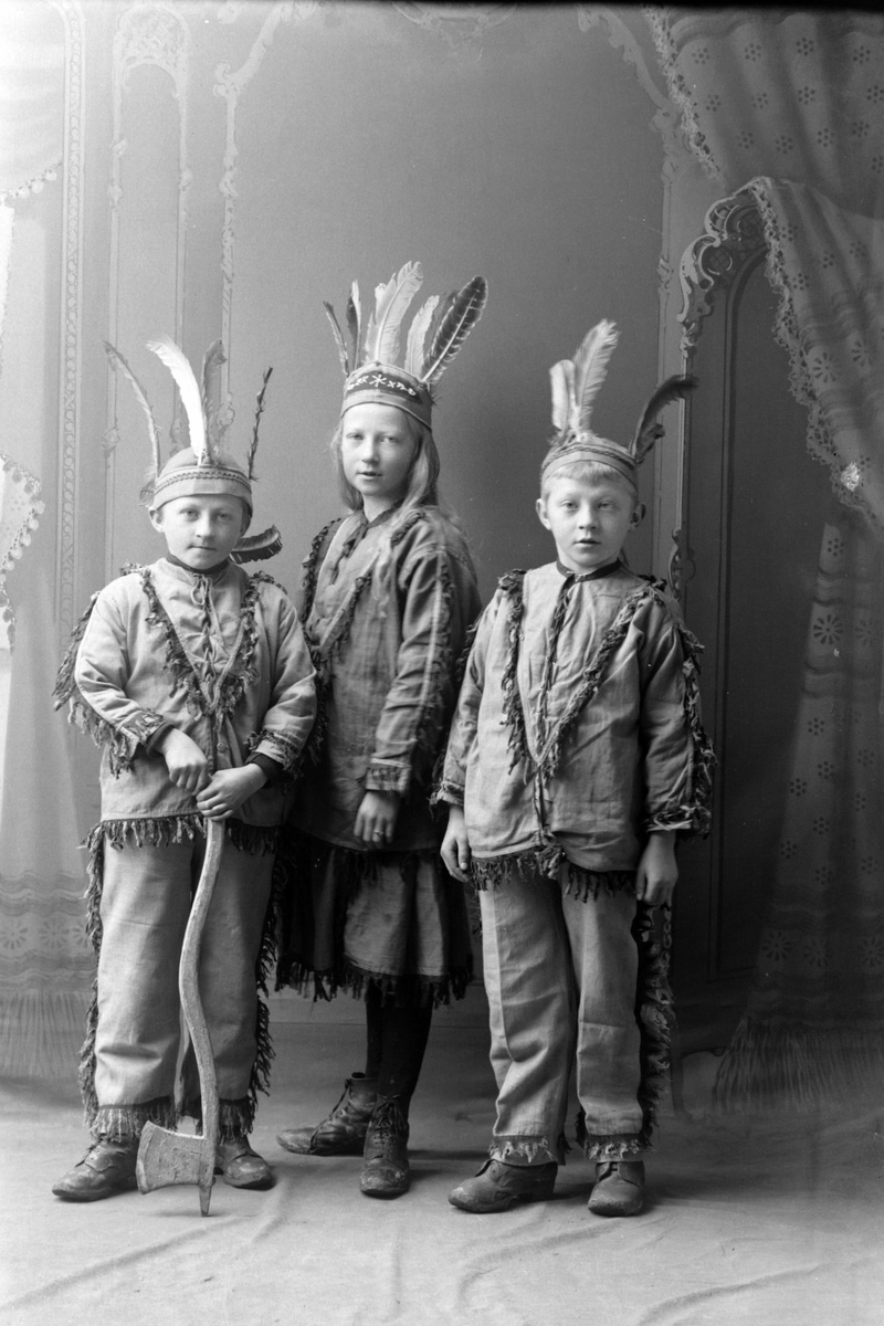 Studioportrett av tre barn utkledd som indianere.