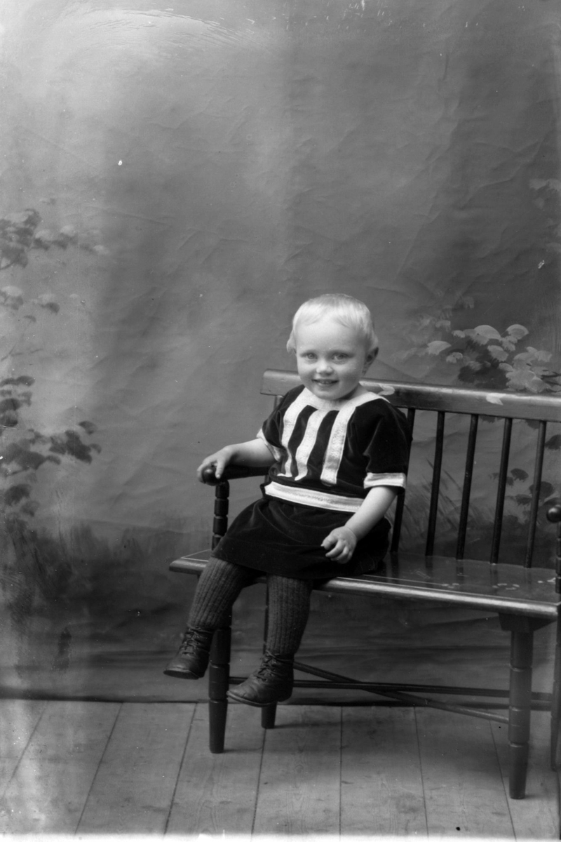 Studioportrett av et lite barn på en benk.