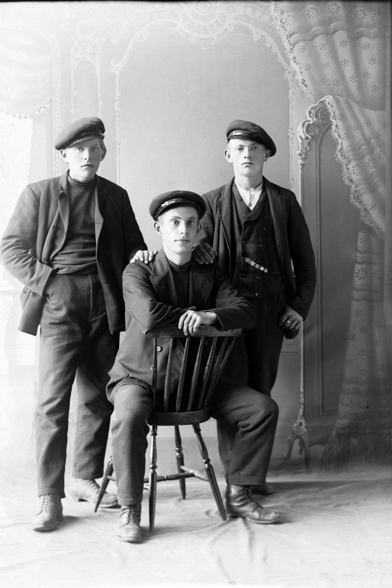 Studioportrett av tre unge menn med kasjettluer.