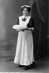 Studioportrett av en servitrise som holder en kake.