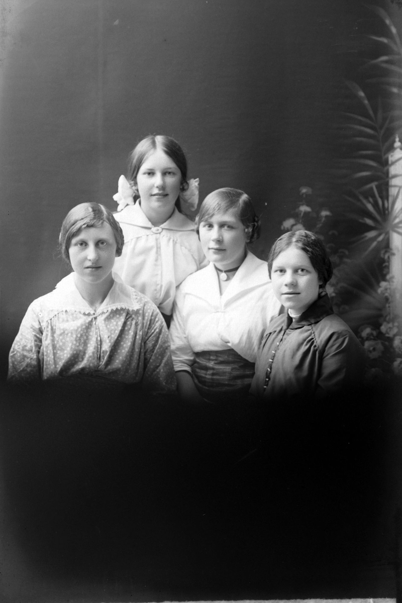 Studioportrett av fire unge kvinner i halvfigur.