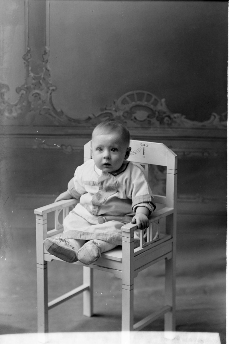 Studioportrett av et lite barn på en stol.