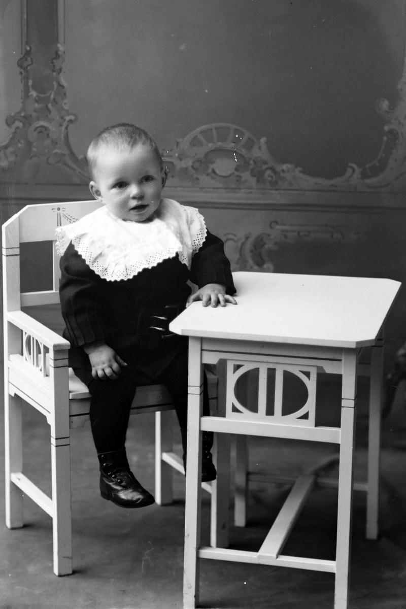Studioportrett av et lite barn ved et bord.