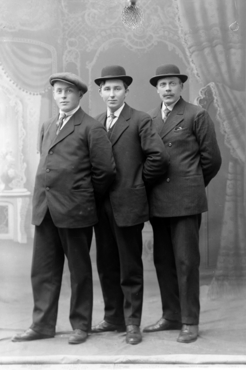 Studioportrett av tre menn i helfigur.
