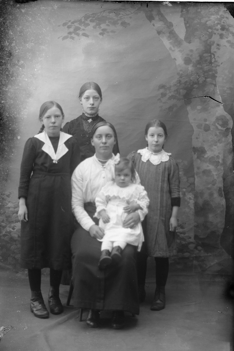 Studioportrett av en kvinne omgitt av fire barn.