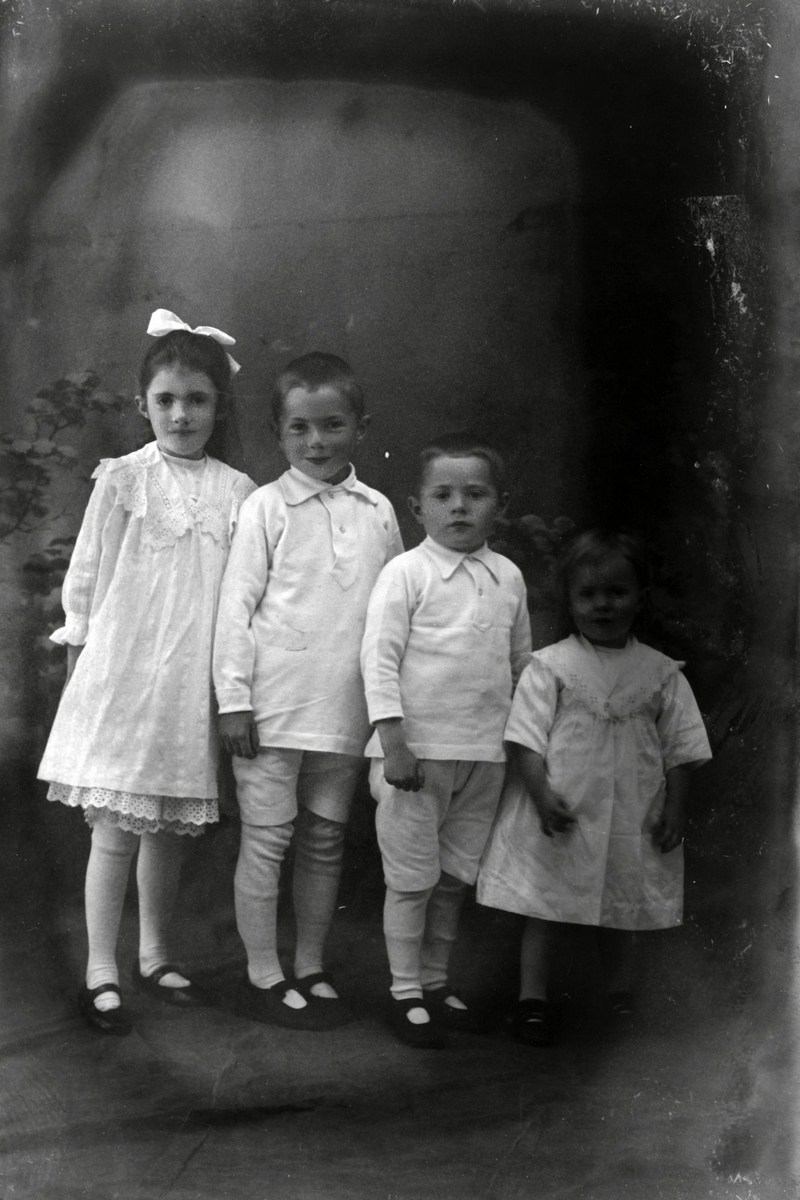 Studioportrett av fire barn på rekke.